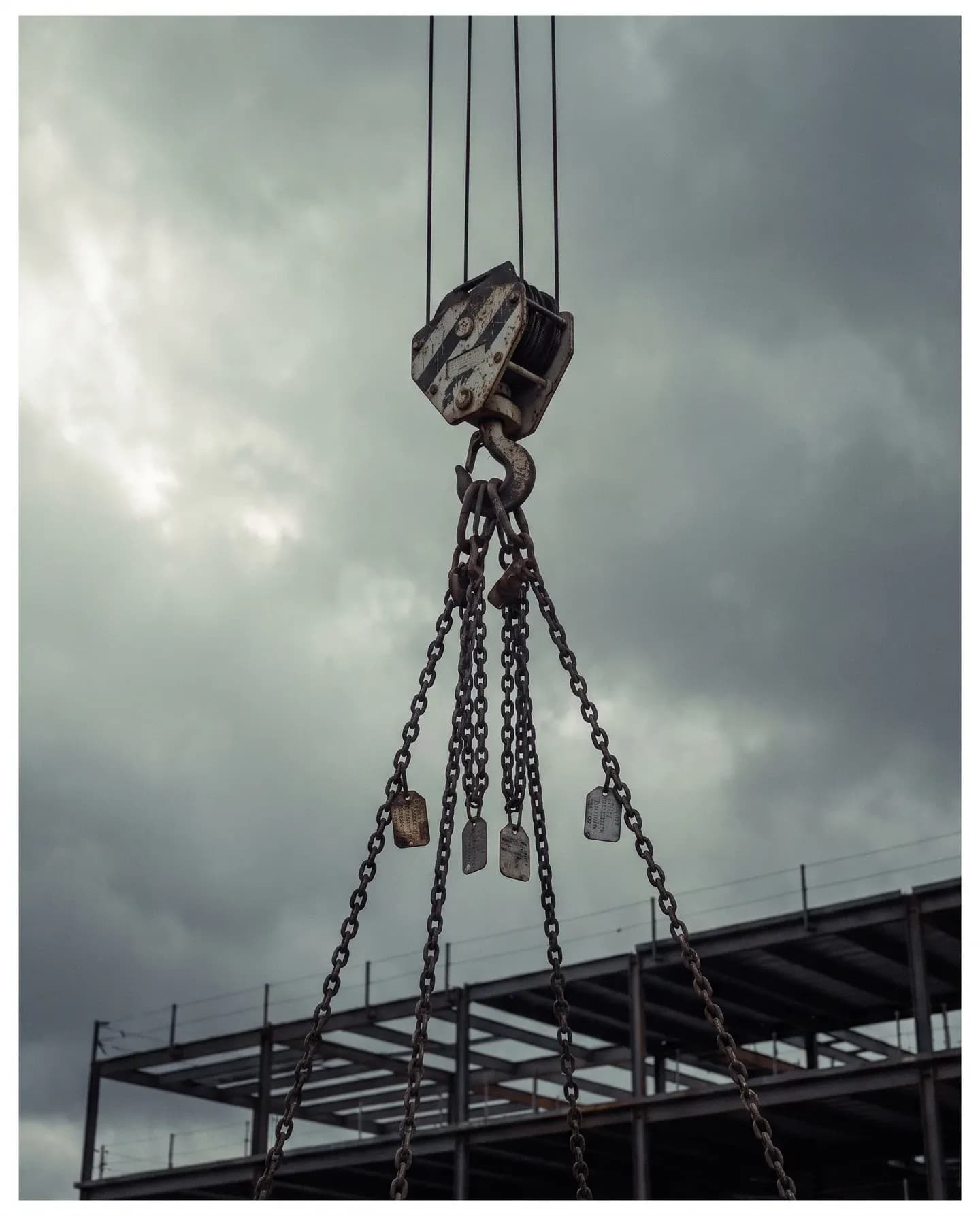 Tower crane hook block with a four-leg chain sling above a steel frame